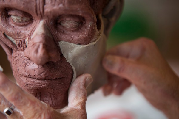 Human head sculpted in clay, applying the skin