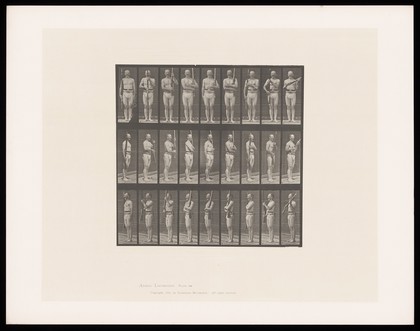 A man in loin cloth and belt stands to attention, a rifle in his right hand, transfers it to his left then holds it at an angle across his torso. Collotype after Eadweard Muybridge, 1887.