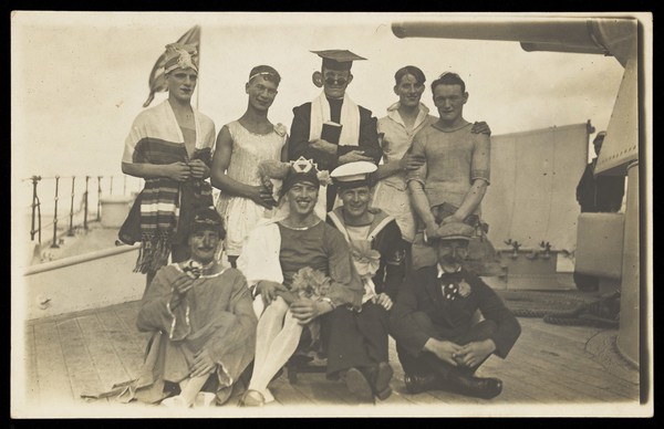 Nine men dressed up on deck. Photographic postcard, 192-.