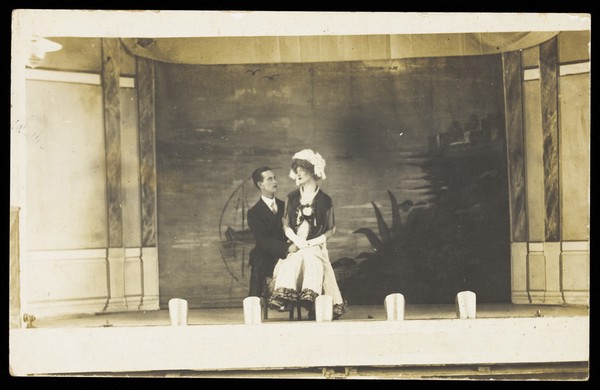Two men seated together on stage. Photographic postcard, 191-.