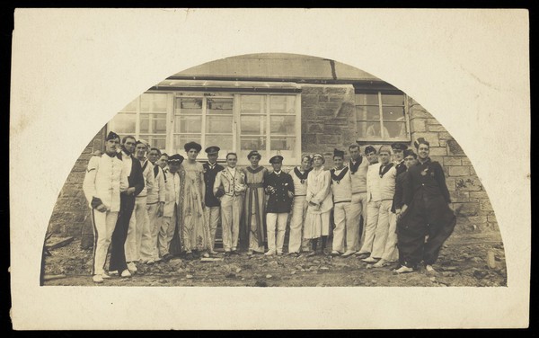 Sailors with men in drag outside a building. Photographic postcard, 191-.