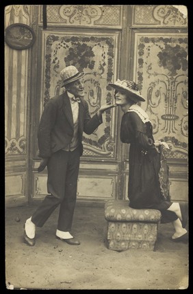 French prisoners of war, one in drag, performing a show at Sennelager prisoner of war camp in Germany. Photographic postcard, 1918.