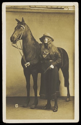 A man dressed in drag as a cowgirl. Photographic postcard, ca. 1915-1920.