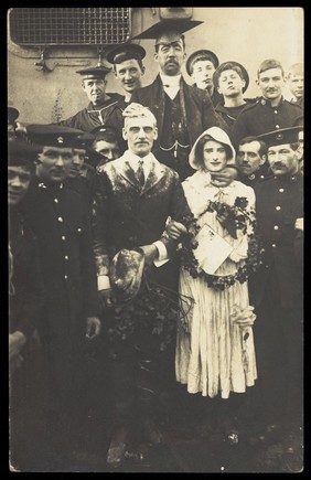 Sailors on H.M.S Dominion, one in bridal drag, conduct a mock wedding on Christmas Day. Photographic postcard, 1915.