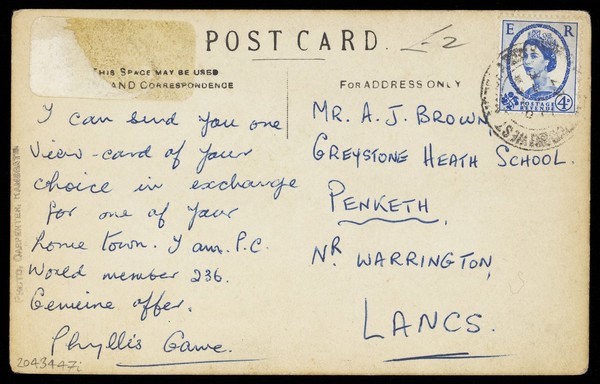 Two men, one in drag, sit together on a bench. Photographic postcard, 190-.
