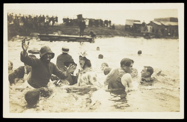 A group of men, one in drag, swimming and playing in a river.