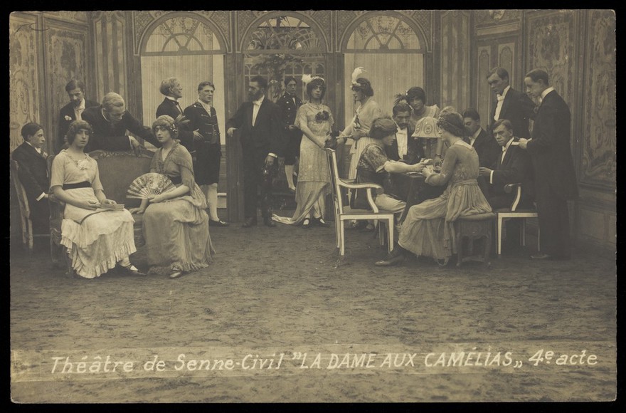 French or Belgian prisoners of war, some in drag, posing on stage during a crowded scene of "La dame aux camélias"; at Sennelager prisoner of war camp in Germany. Photographic postcard, 191-.