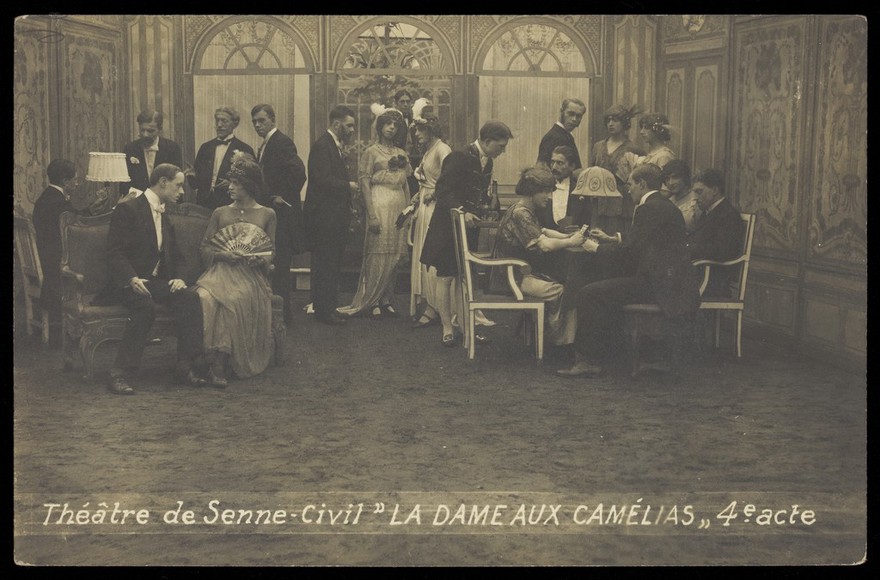 French or Belgian prisoners of war, some in drag, posing on stage during a crowded scene of "La dame aux camélias"; at Sennelager prisoner of war camp in Germany. Photographic postcard, 191-.