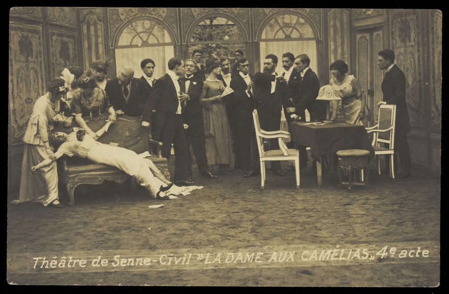 French or Belgian prisoners of war, some in drag, posing on stage during a crowded scene of "La dame aux camélias"; at Sennelager prisoner of war camp in Germany. Photographic postcard, 191-.