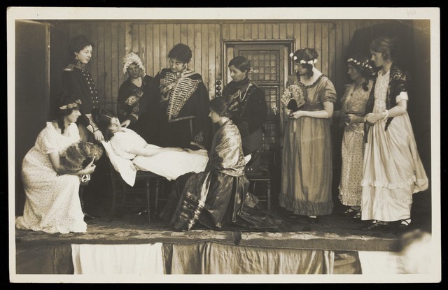 Amateur actors, some in drag, on stage attending to the death of a female character. Photographic postcard, 191-.
