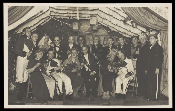 German actors, some in drag, gather on stage at a party. Photographic postcard, 1930-45.
