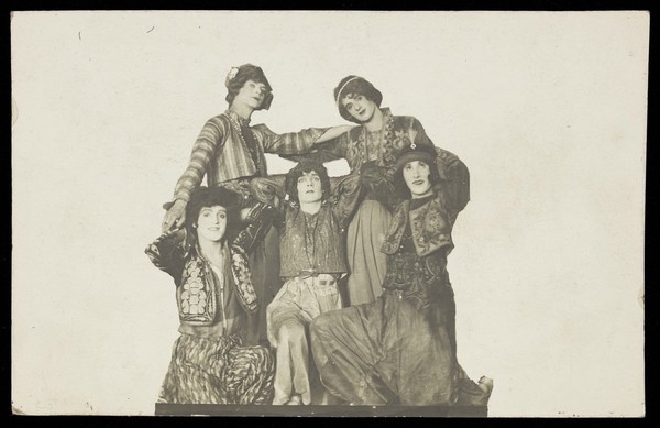 Russian soldiers in drag, posing very close together, in front of a plain background. Photographic postcard, 191-.