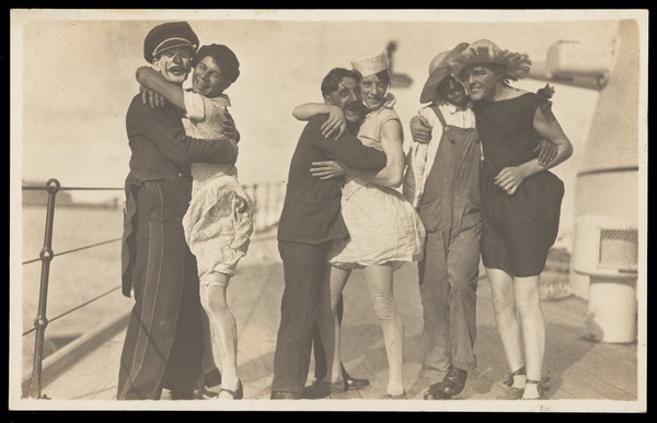 Sailors, some in drag, pose as three couples on the deck of a ship. Photographic postcard, 192-.