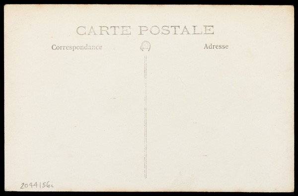 A theatre set with a piano beside it and a portrait of a woman mounted at the foot of the stage. Photographic postcard, 191-.