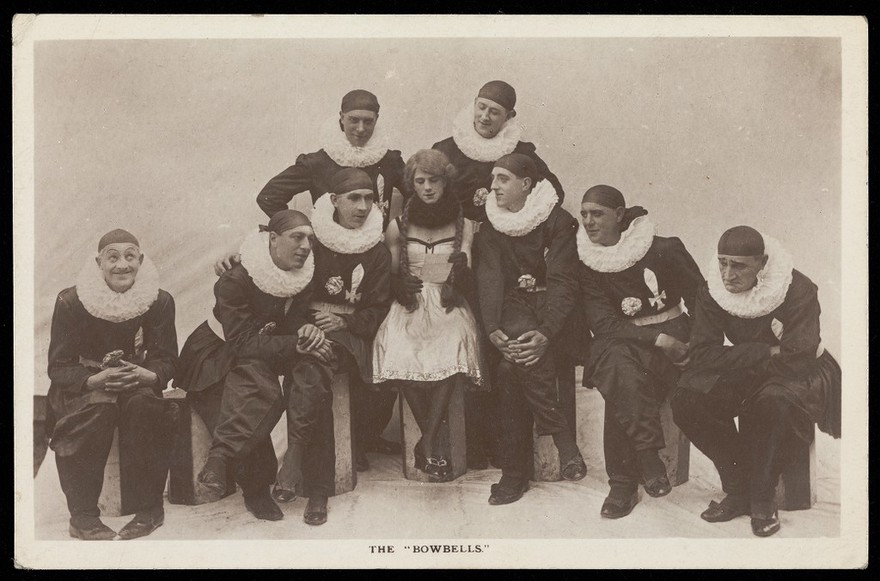 Soldiers, one in drag, performing in a concert party as "The Bow Bells"; posing for a group portrait. Photographic postcard, 191-.