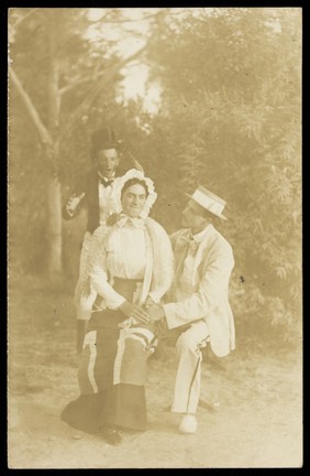 Three actors, one in female dress, posing in a tableau.