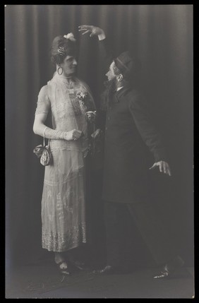 Ralph Mellor in drag and another actor perform a scene in Trilby. Photographic postcard by L.S. Langfier, 192-.