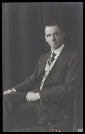 Ralph Mellor, seated dressed in smart attire. Photographic postcard by L.S. Langfier, 192-.