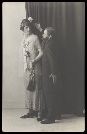 Ralph Mellor in drag and another actor perform a scene in Trilby. Photographic postcard by L.S. Langfier, 192-.