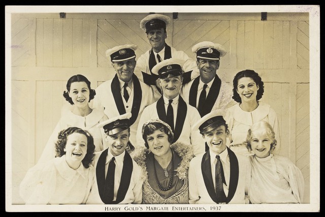 Members of "Harry Gold's Margate Entertainers", one in drag, pose for a group portrait. Photographic postcard, 1937.
