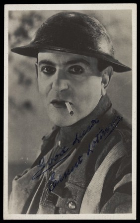 Ernest Lotinga in battledress and wearing makeup. Photographic postcard, 193-.