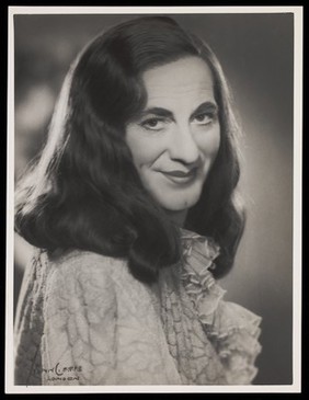 An actor in drag, posing for a portrait. Photograph by Mme Yvonne, 194-.