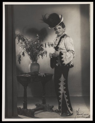 An actor in drag, posing in a studio. Photograph by Mme Yvonne, 194-.