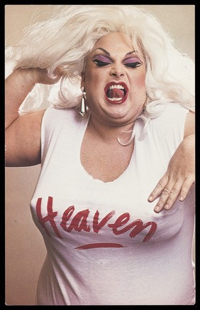 "Divine" in character, wearing a "Heaven" t-shirt. Colour photographic postcard, 198-.