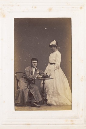 Two men, one in drag, acting out a scene. Photograph, 189-.