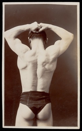 An athletic man poses with his back to the viewer. Photographic postcard, 193-.