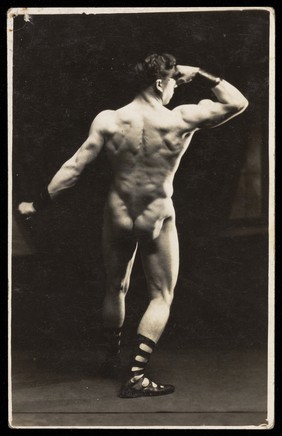 A bodybuilder poses with his back to the viewer. Photographic postcard, 192-.