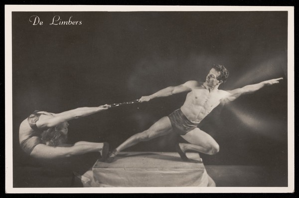 Two acrobats performing on a plinth. Photographic postcard, 19--.