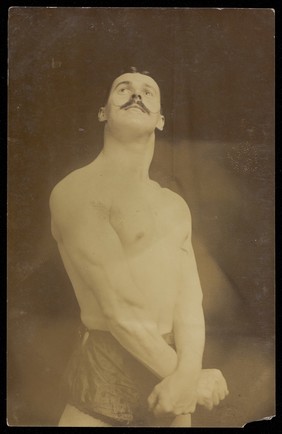 A wrestler (?) gazing upwards. Photographic postcard, 19--.