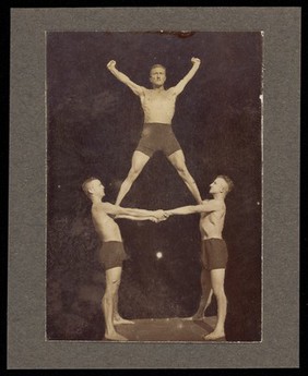 Three male acrobats perform a human-pyramid. Photograph, 19--.