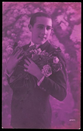 A young man holding roses. Colour photographic postcard, 192-.