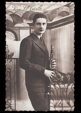 A man holding a clarinet to celebrate Saint Cecilia's Day. Photographic postcard, 192-.