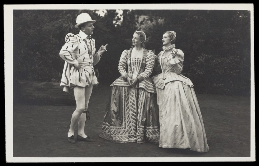 An actor in Elizabethan costume in conversation with two actresses. Photographic postcard by J.W. Debenham, 193-.