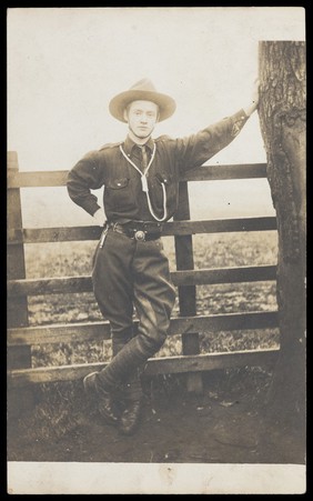 A senior Scout poses next to a tree. Photographic postcard, ca. 1920.