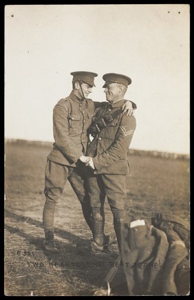 Two soldiers embrace in a field. Photographic postcard, 191-.