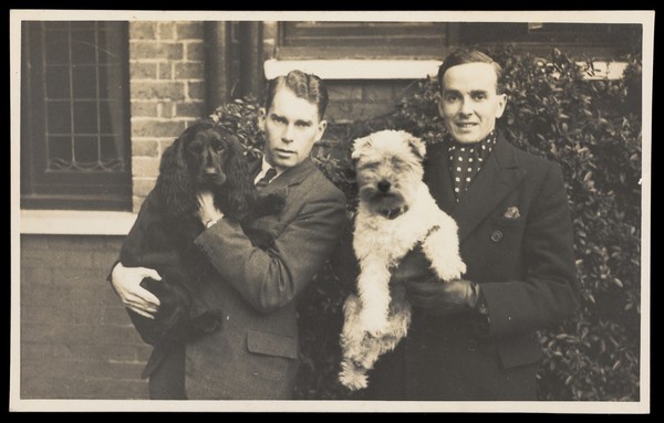 Two men holding their dogs. Photographic postcard, 193-.