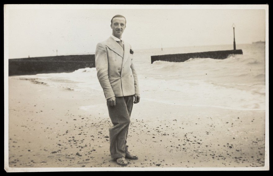 A man posing on a beach in formal attire. Photographic postcard by Jerome Ltd., 192-.