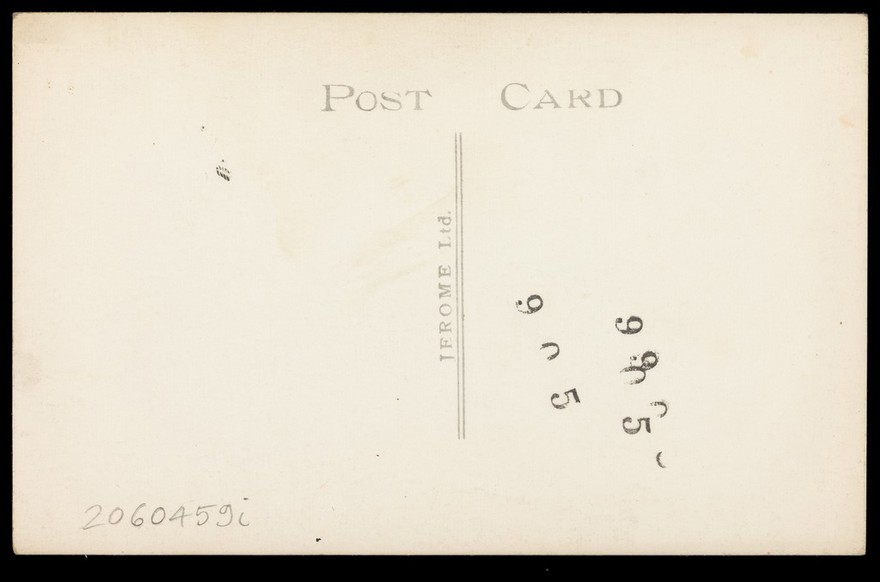 A man in a long coat paddling in the sea. Colour photographic postcard, 192-.