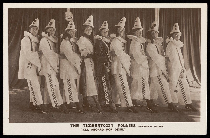Actors dressed as a clowns, performing for "The Timbertown Follies", at a prisoner of war camp in Groningen. Photographic postcard, 191-.