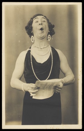 A man in drag singing. Photographic postcard, 193-.