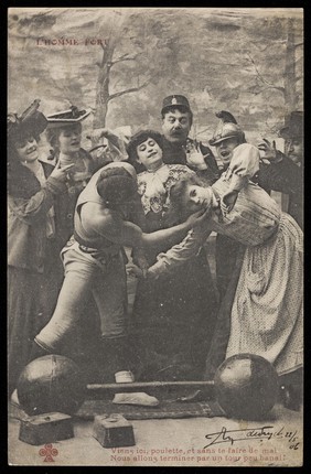 A strongman (Emile de Suyck?) invites a woman to volunteer to help him in his final feat. Process print, 1906 (?).