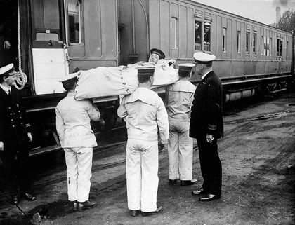 Naval Nurse and Red Cross Train at Chatham. Fleet Surgeon Jones, Medical Transport Officer, speaking to one of the cot cases.