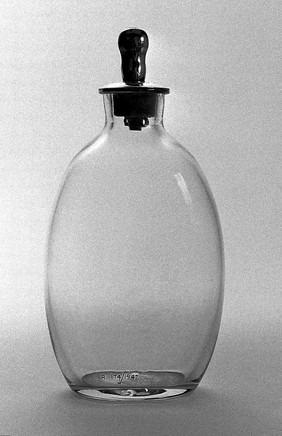 Glass feeding bottle with silver nipple.