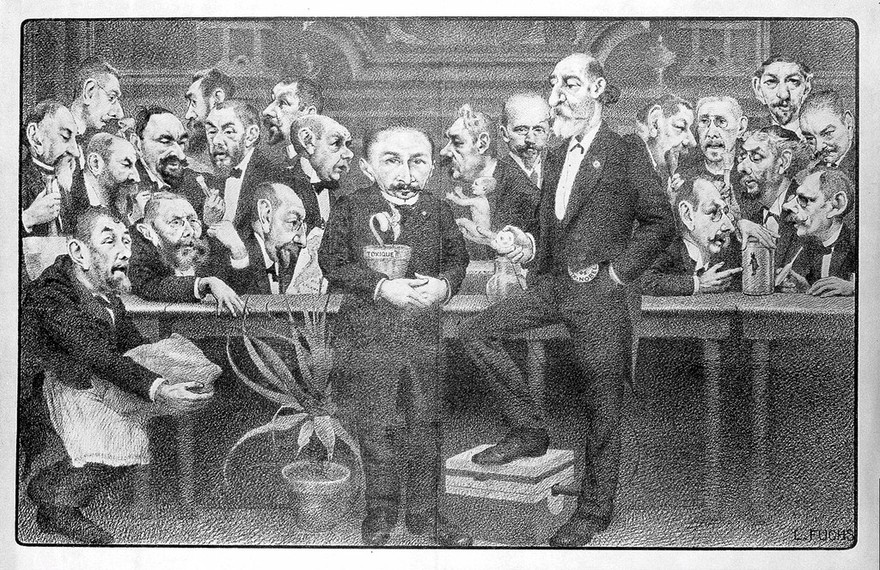 Men of various sizes are sitting on chairs watching a very tall man (Moissan?). Lithograph by L. Fuchs.