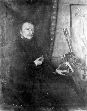 Portrait of W. H. Dallinger, seated at r. to microscope