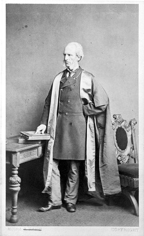 Portrait of Frederick Legros Clark, full length, standing, in academic gown.